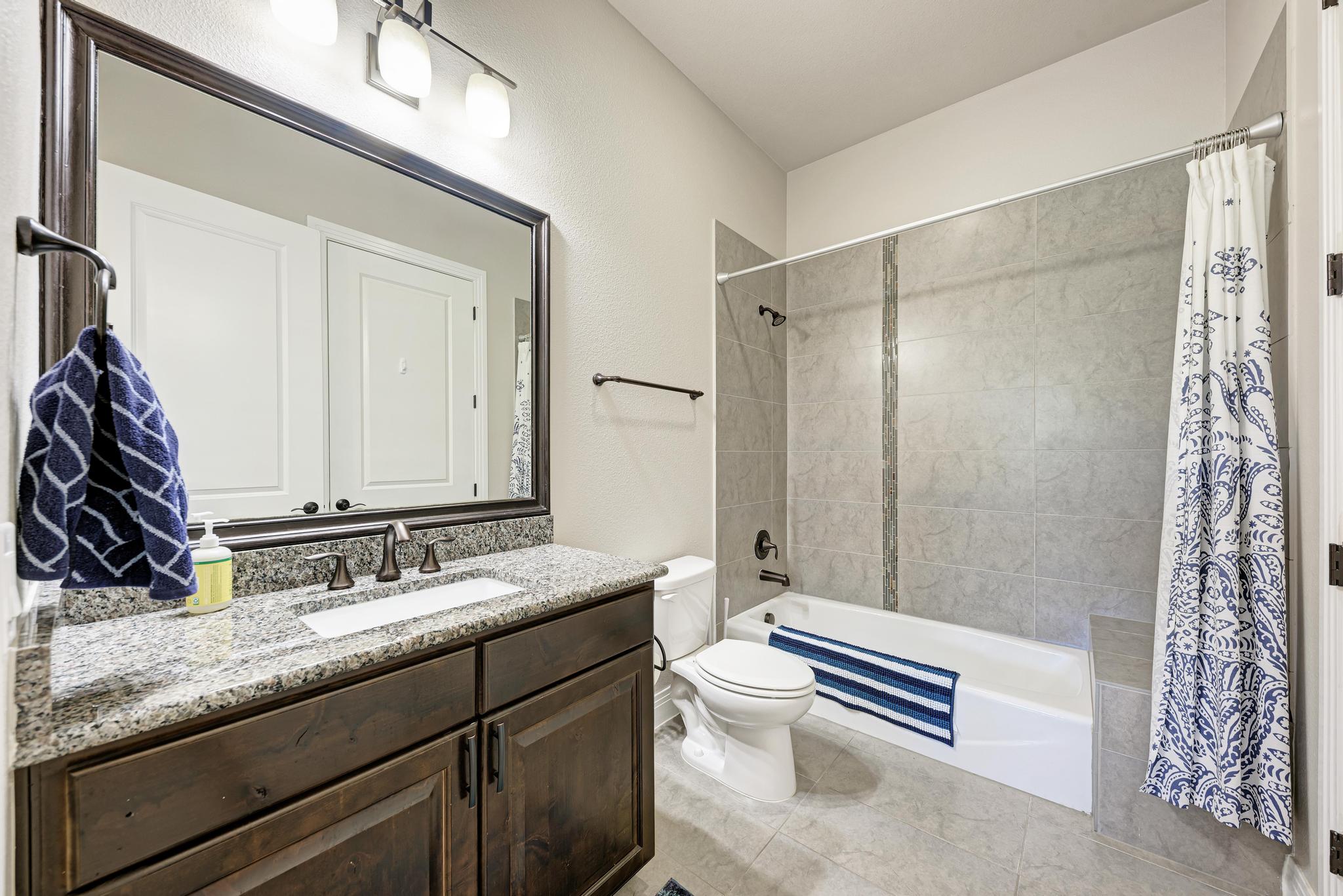 2601 North Quinlan Park Road, Unit 506 Austin, TX 78732 - Photo 29 of 39 A well-appointed bath features a granite vanity and a tiled shower-tub combination.