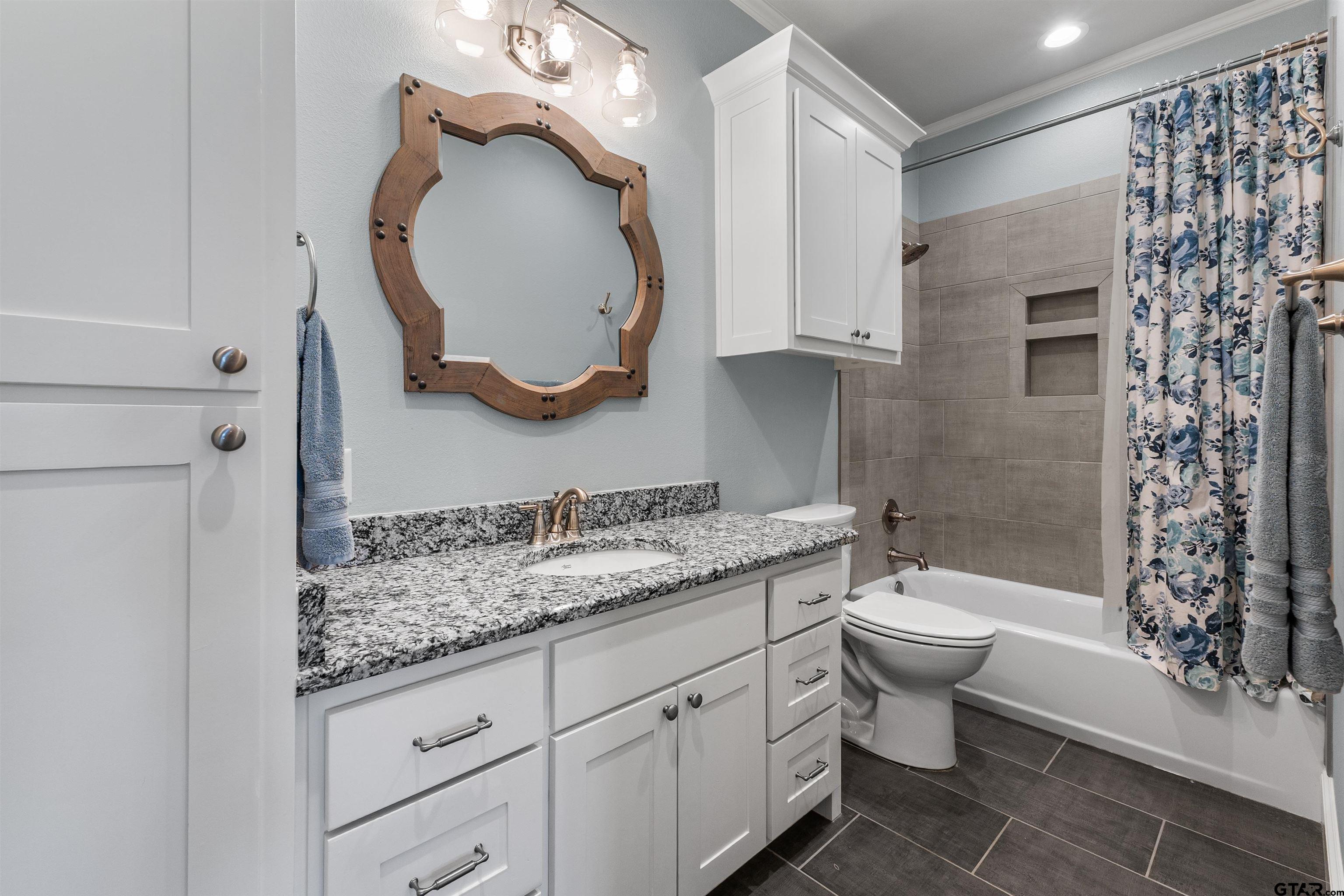 1111 Cambridge Bend Tyler, TX 75703 - Photo 27 of 42 a bathroom with a granite countertop toilet a sink and a mirror