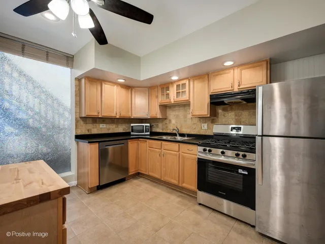a kitchen with stainless steel appliances granite countertop a refrigerator a stove and a sink