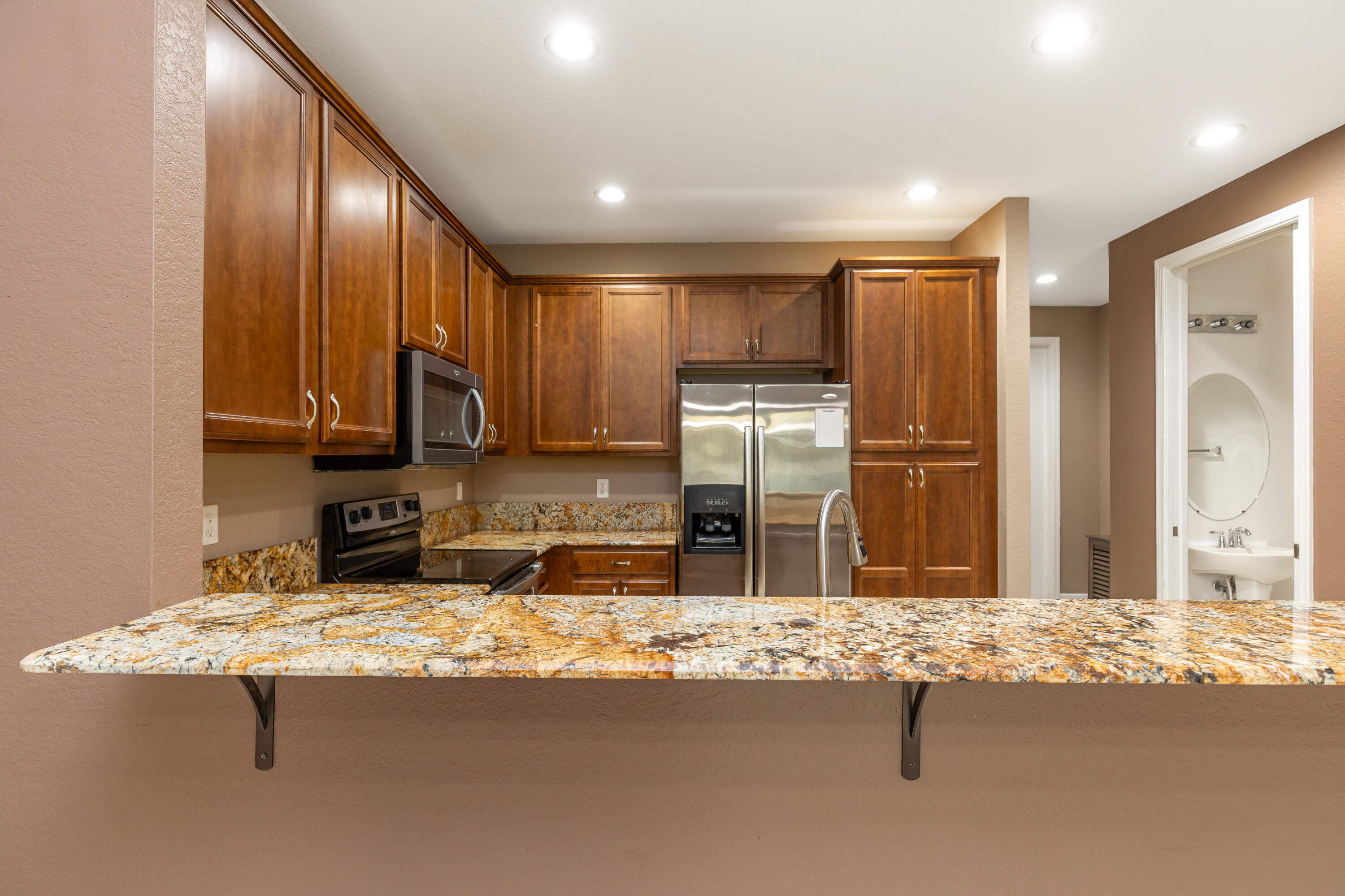 7782 Paddock Place Davie, FL 33328 - Photo 11 of 40 a kitchen with kitchen island granite countertop a sink refrigerator and cabinets