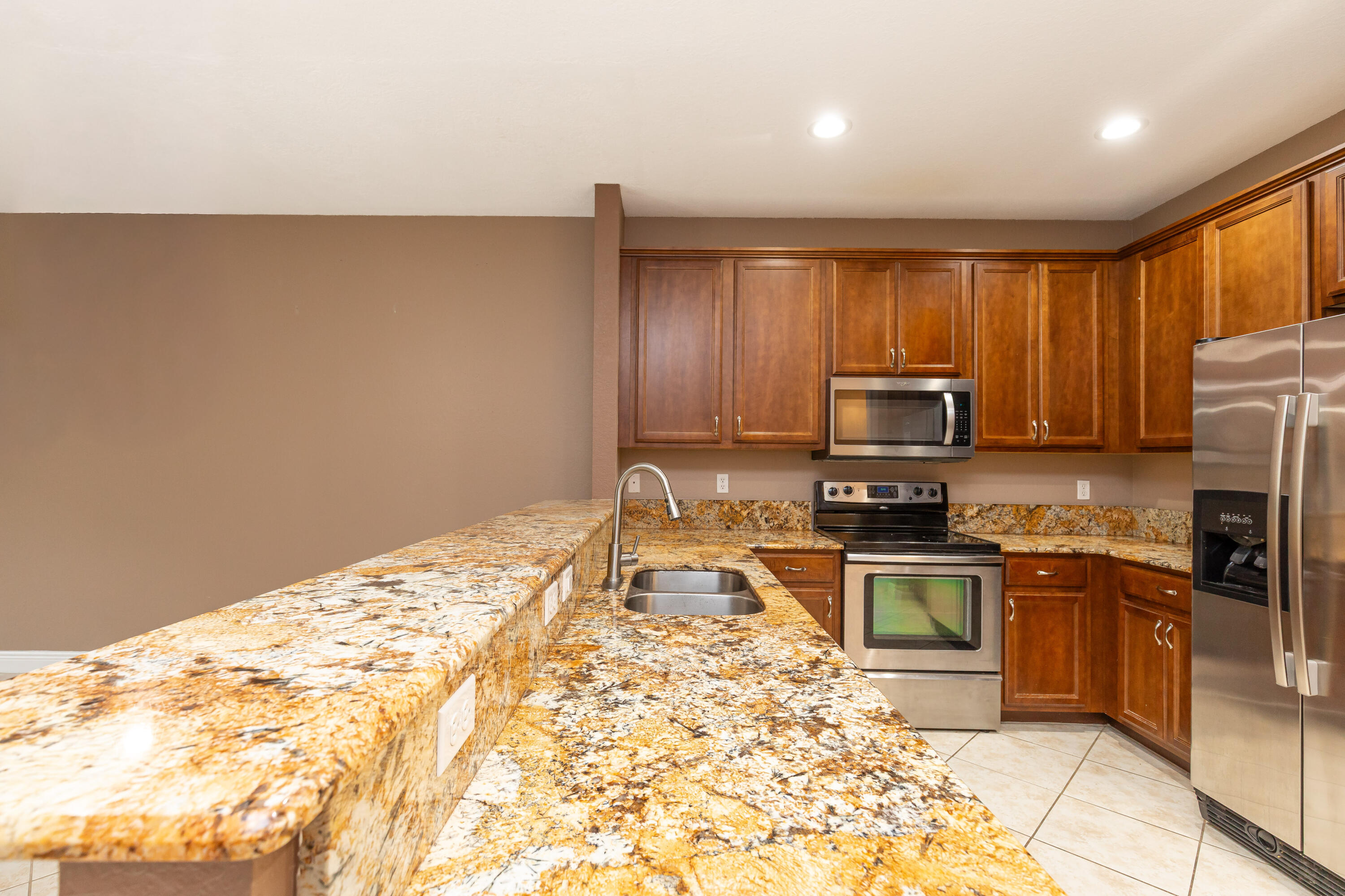 7782 Paddock Place Davie, FL 33328 - Photo 8 of 40 a kitchen with granite countertop a refrigerator and a stove top oven