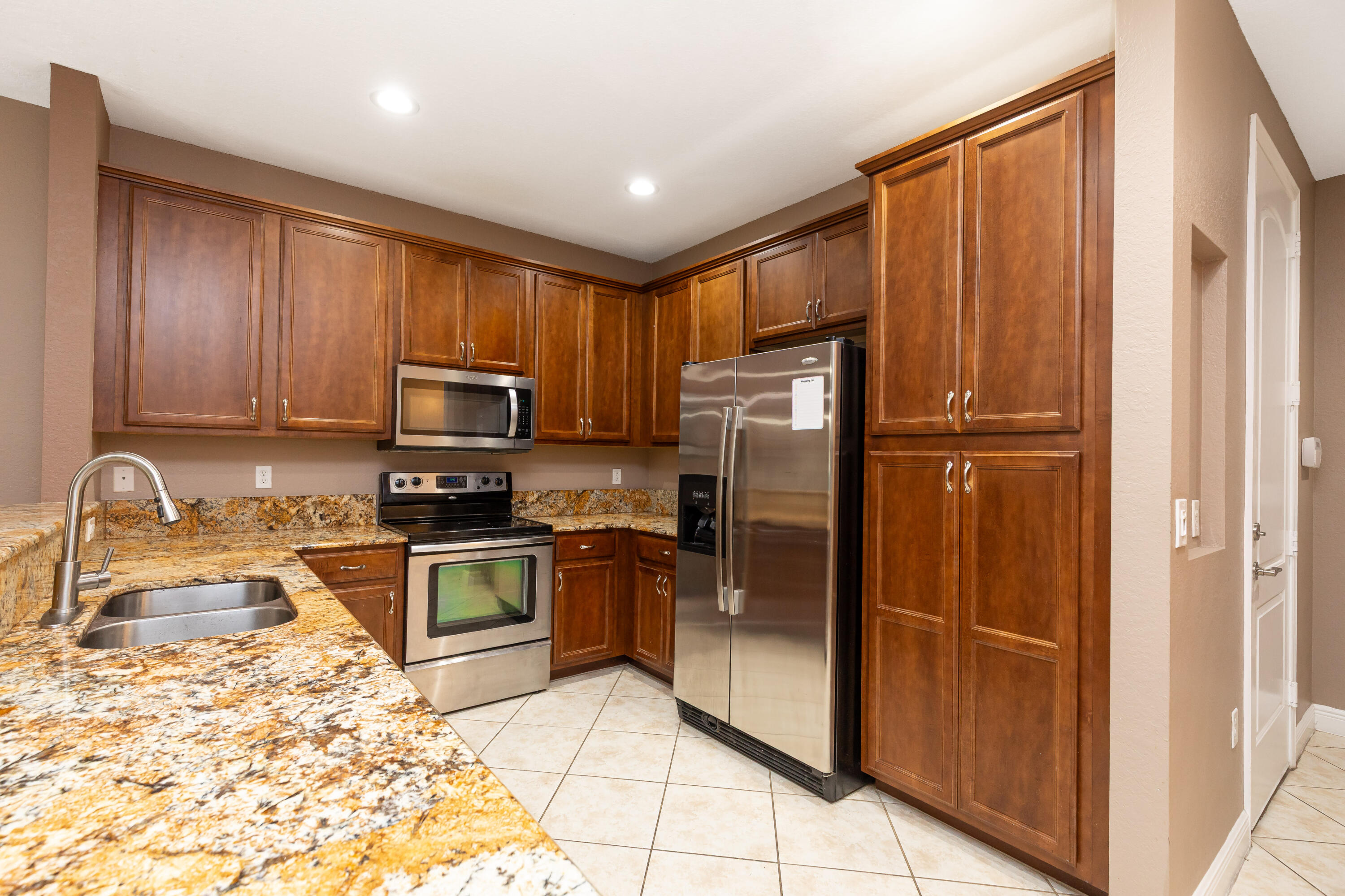 7782 Paddock Place Davie, FL 33328 - Photo 10 of 40 a kitchen with granite countertop stainless steel appliances a refrigerator a stove top oven and sink
