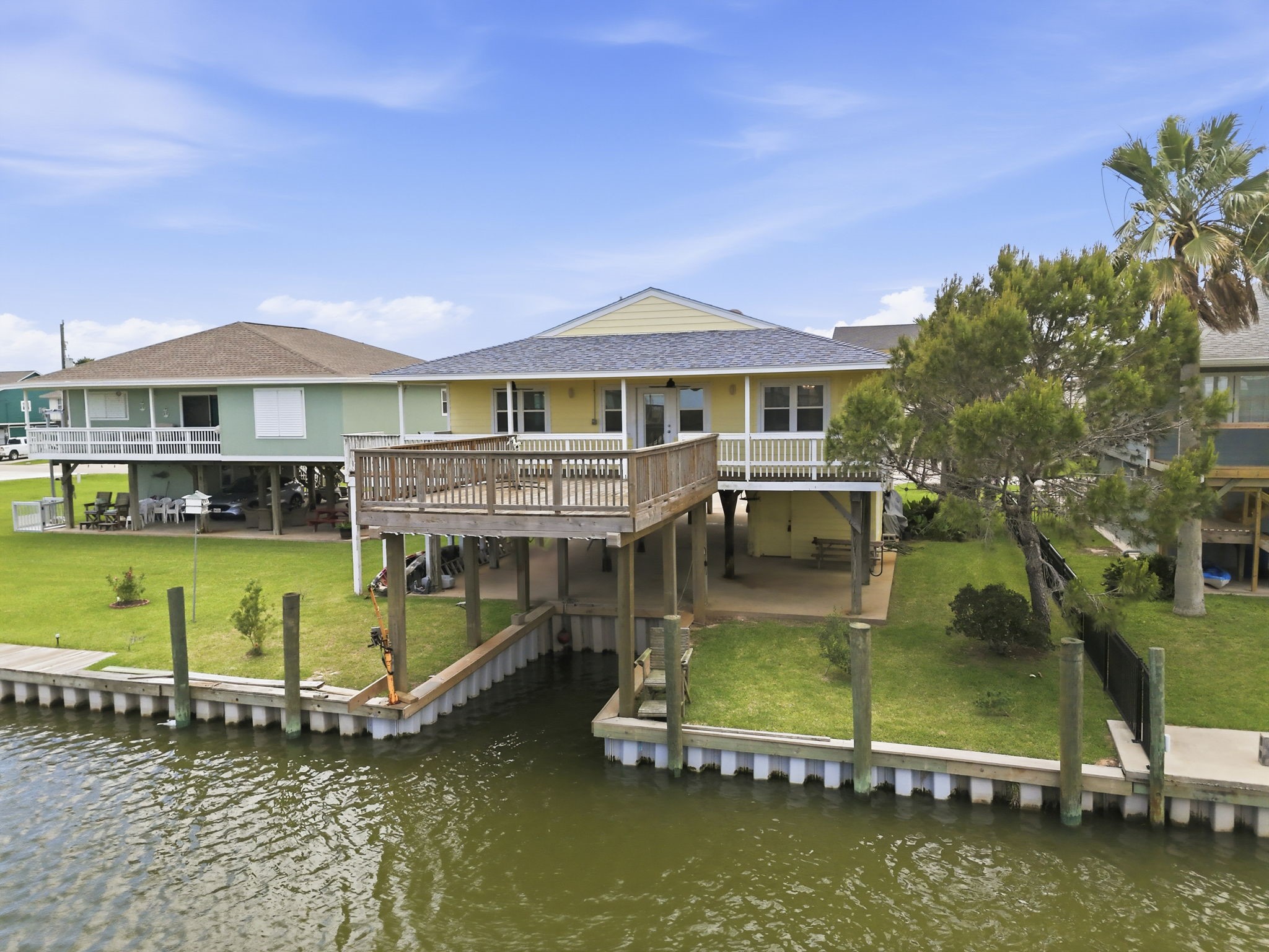 119 Sand Shoals Road Freeport, TX 77541 - Photo 11 of 34 Aerial of canal-front lot — private bulkhead, dock, ground-level covered parking, and grassy backyard along the water.