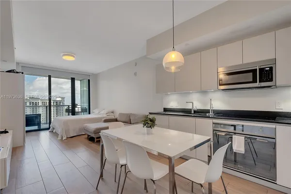 a kitchen with stainless steel appliances granite countertop a stove a sink dishwasher a dining table and chairs with wooden floor