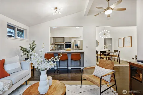 a living room with furniture kitchen view and a chandelier