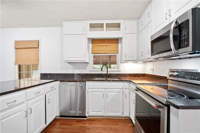 a kitchen with stainless steel appliances granite countertop a sink a stove a microwave and wooden cabinets