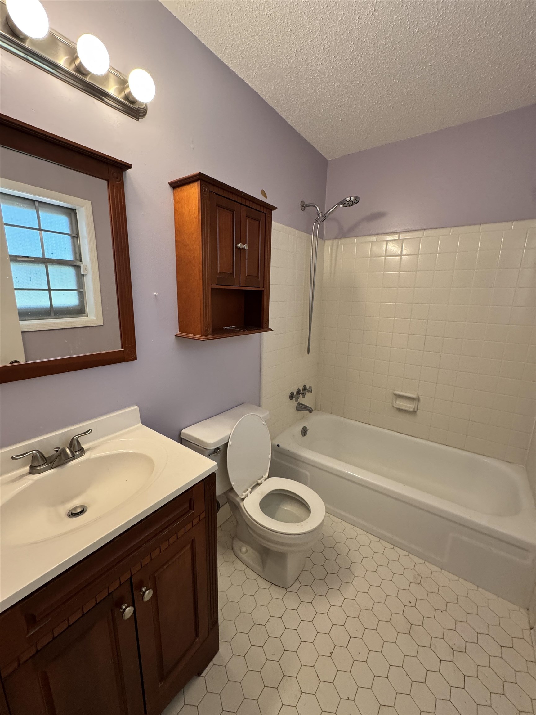 5520 Wagon Rd Gap, Unit GAP Memphis, TN 38134 - Photo 12 of 19 Bathroom featuring a white bathtub with tile surround, white hexagonal floor tiles, a vanity with wood-finish cabinetry, a white countertop, and a wall-mounted medicine cabinet