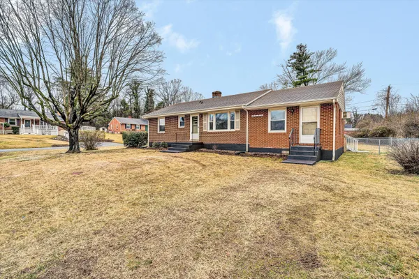 a front view of a house with a yard covered with snow and trees