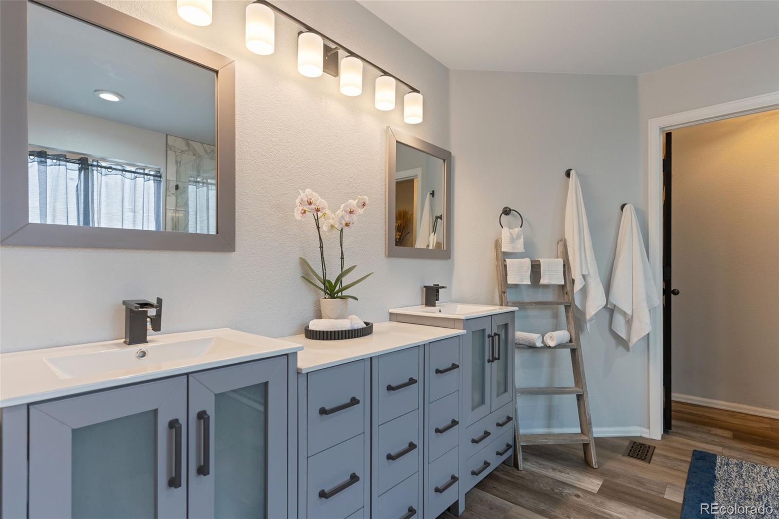 6794 West 98th Circle Westminster, CO 80021 - Photo 21 of 43 a bathroom with a double vanity sink a mirror and a shower