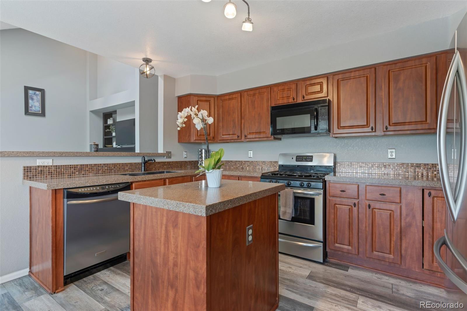 6794 West 98th Circle Westminster, CO 80021 - Photo 7 of 43 a kitchen with stainless steel appliances granite countertop a stove top oven a sink and a microwave