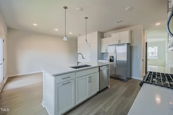 a kitchen with stainless steel appliances a sink a stove a refrigerator a center island and cabinets