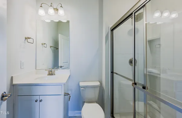 a bathroom with a shower sink vanity mirror and toilet