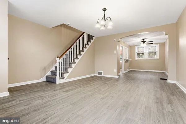 a view of an empty room with wooden floor and stairs