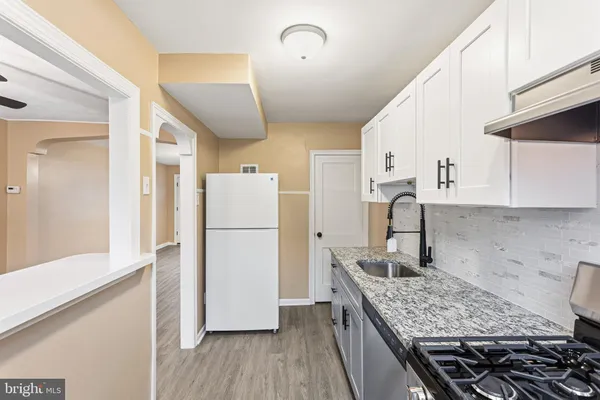 a kitchen with a refrigerator a sink and wooden floor