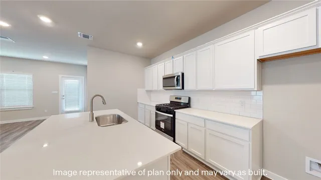 a kitchen with stainless steel appliances a sink a stove a microwave a sink a refrigerator and cabinets