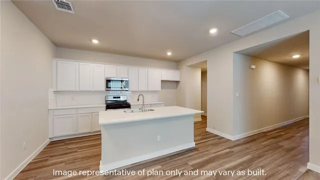 a kitchen with stainless steel appliances granite countertop a refrigerator sink and white cabinets