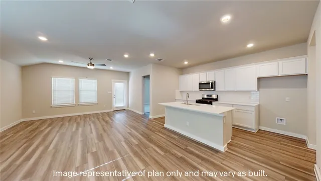 a kitchen with a sink a stove a refrigerator and white cabinets