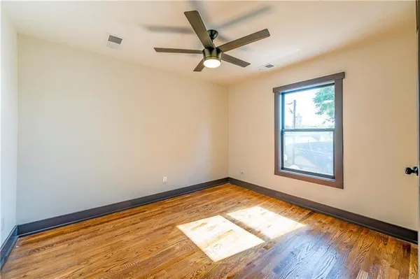 a view of empty room with wooden floor and fan