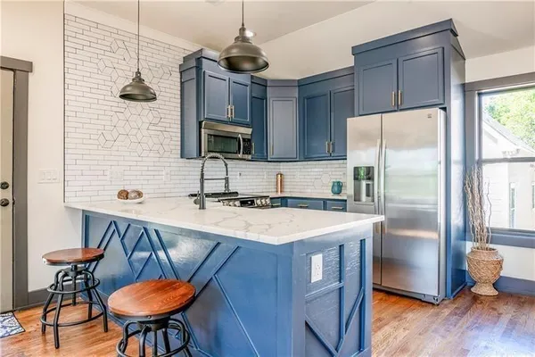 a kitchen with stainless steel appliances a table chairs refrigerator and microwave