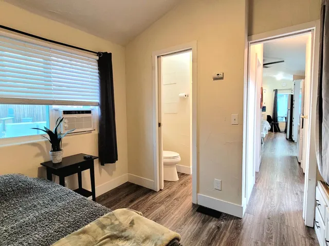 a view of a hallway with wooden floor and a bathroom