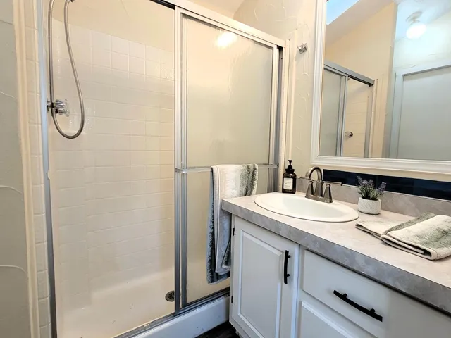 a bathroom with a granite countertop sink a mirror a vanity and a shower