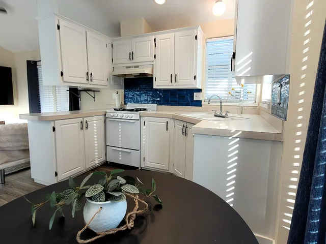 a kitchen with stainless steel appliances granite countertop a sink a stove and white cabinets