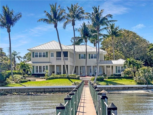 a view of swimming pool with lawn chairs and palm trees