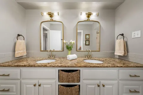 a bathroom with double vanity sinks granite vanity and a mirror