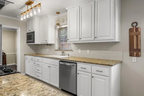 a kitchen with granite countertop white cabinets and sink