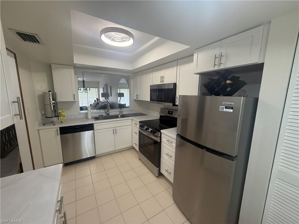 905 Augusta Boulevard Naples, FL 34113 - Photo 5 of 20 a kitchen with a sink a refrigerator a microwave and cabinets