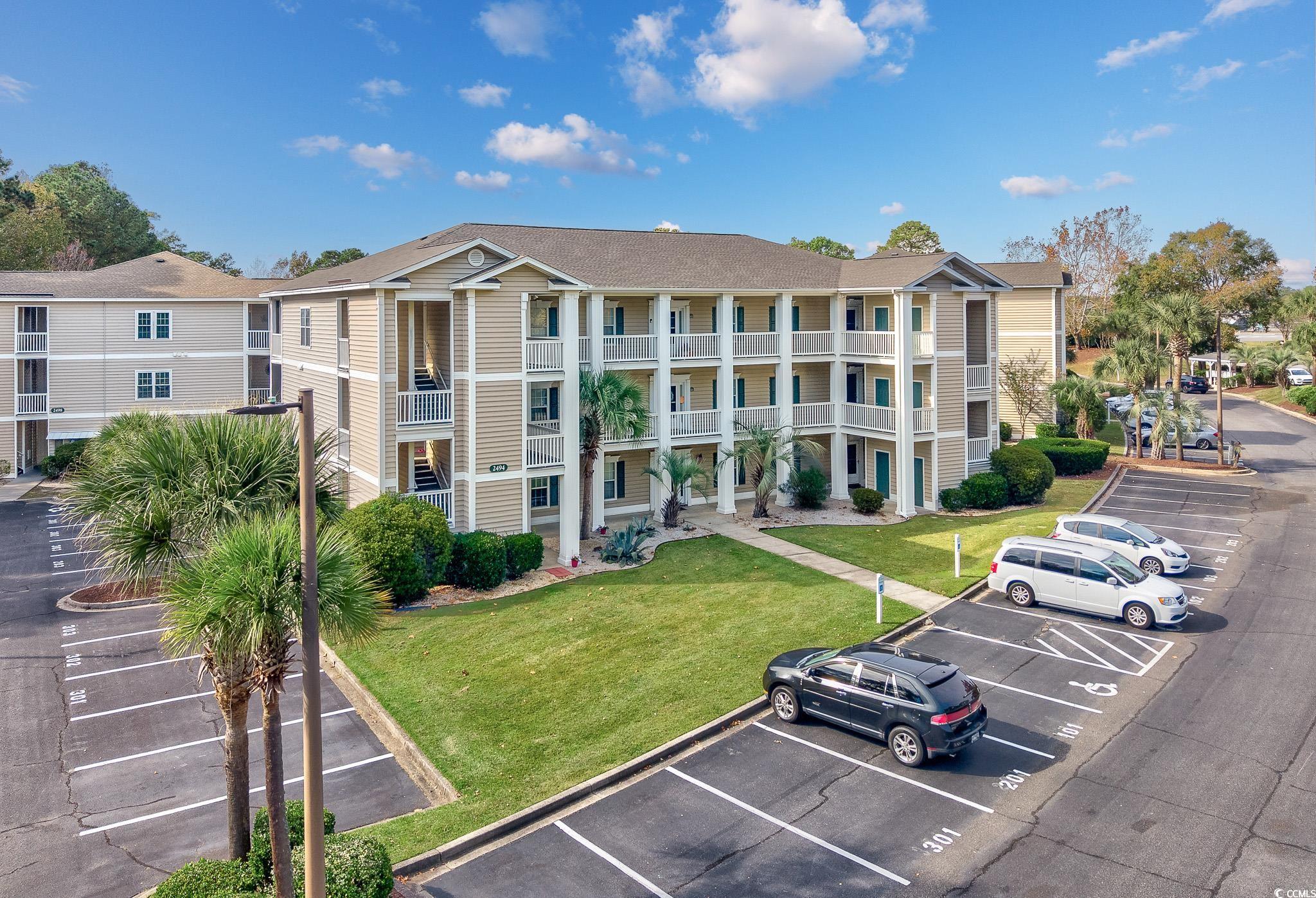View of apartment building / complex with uncovered parking