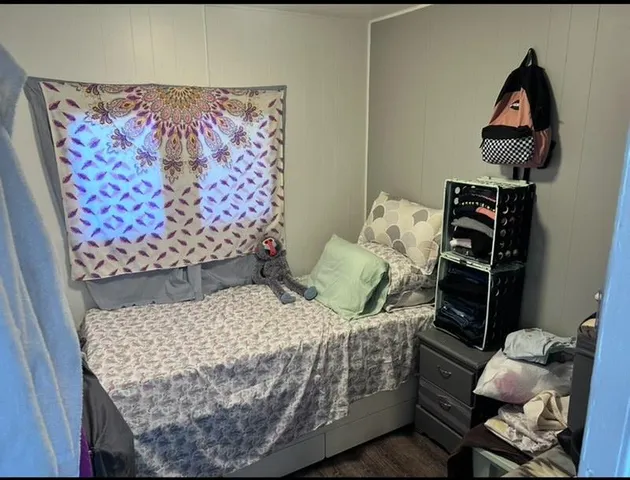 a bed sitting in a bedroom next to a lamp with wooden floor