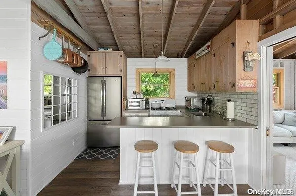a kitchen with stainless steel appliances granite countertop a refrigerator a stove a sink dishwasher and white cabinets with wooden floor