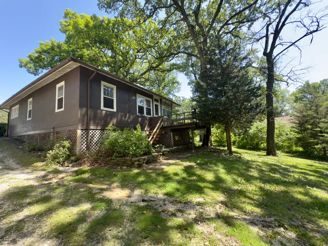 a backyard of a house with plants and large tree