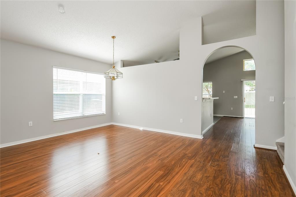1170 Creekview Court St. Cloud, FL 34772 - Photo 4 of 17 an empty room with wooden floor chandelier and windows