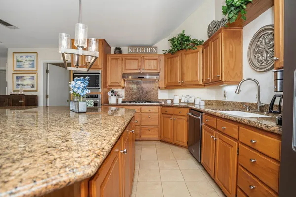a kitchen with kitchen island granite countertop wooden cabinets a sink dishwasher and a stove