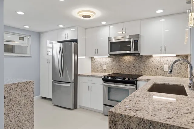 a kitchen with stainless steel appliances granite countertop a refrigerator and a sink
