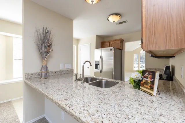 a kitchen with granite countertop a sink stainless steel appliances a counter space and a window