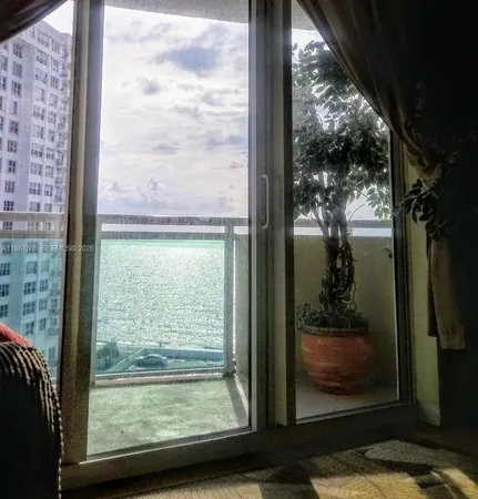 a view of a room with a large window and wooden floor