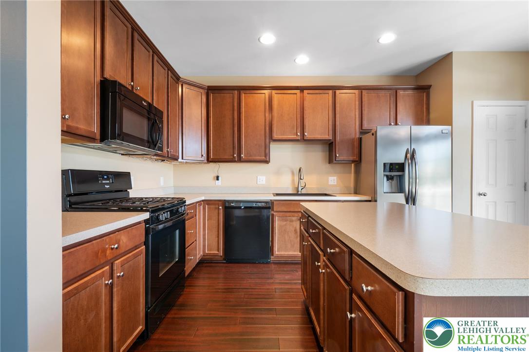 8455 Starling Road Breinigsville, PA 18031 - Photo 7 of 24 A well-equipped kitchen features rich wood cabinetry, durable countertops, and sleek black and stainless steel appliances.