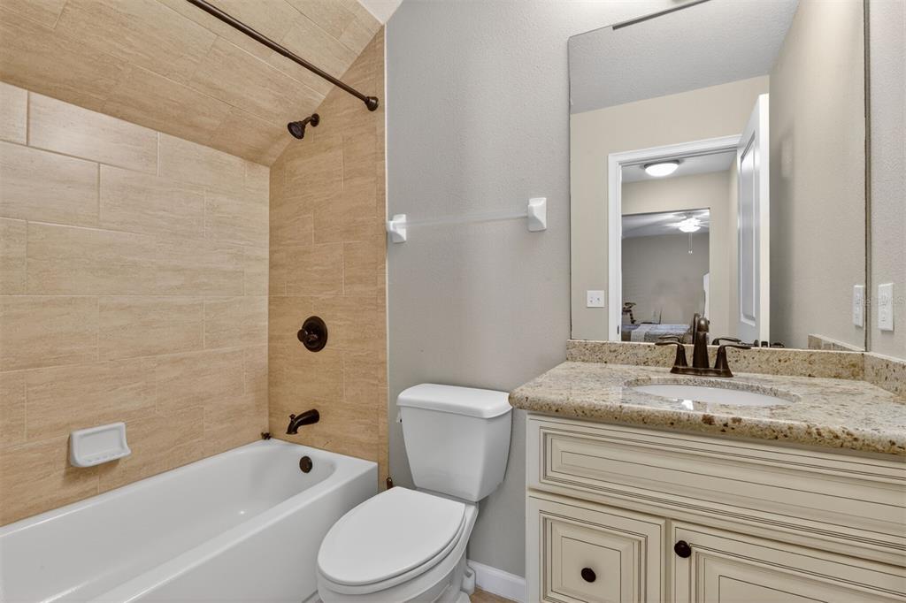 11949 Northwest 13 Road Gainesville, FL 32606 - Photo 42 of 46 a bathroom with a granite countertop toilet a sink and bathtub