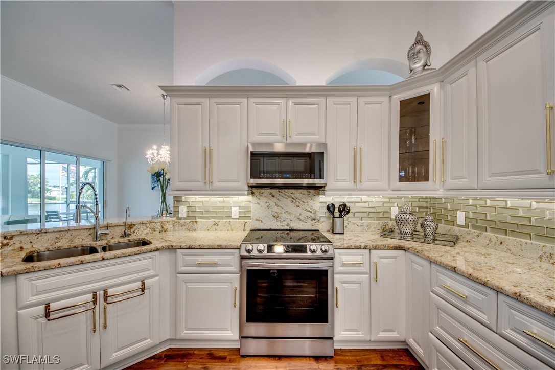 2703 Southwest 43rd Terrace Cape Coral, FL 33914 - Photo 15 of 50 a kitchen with granite countertop a stove sink and microwave