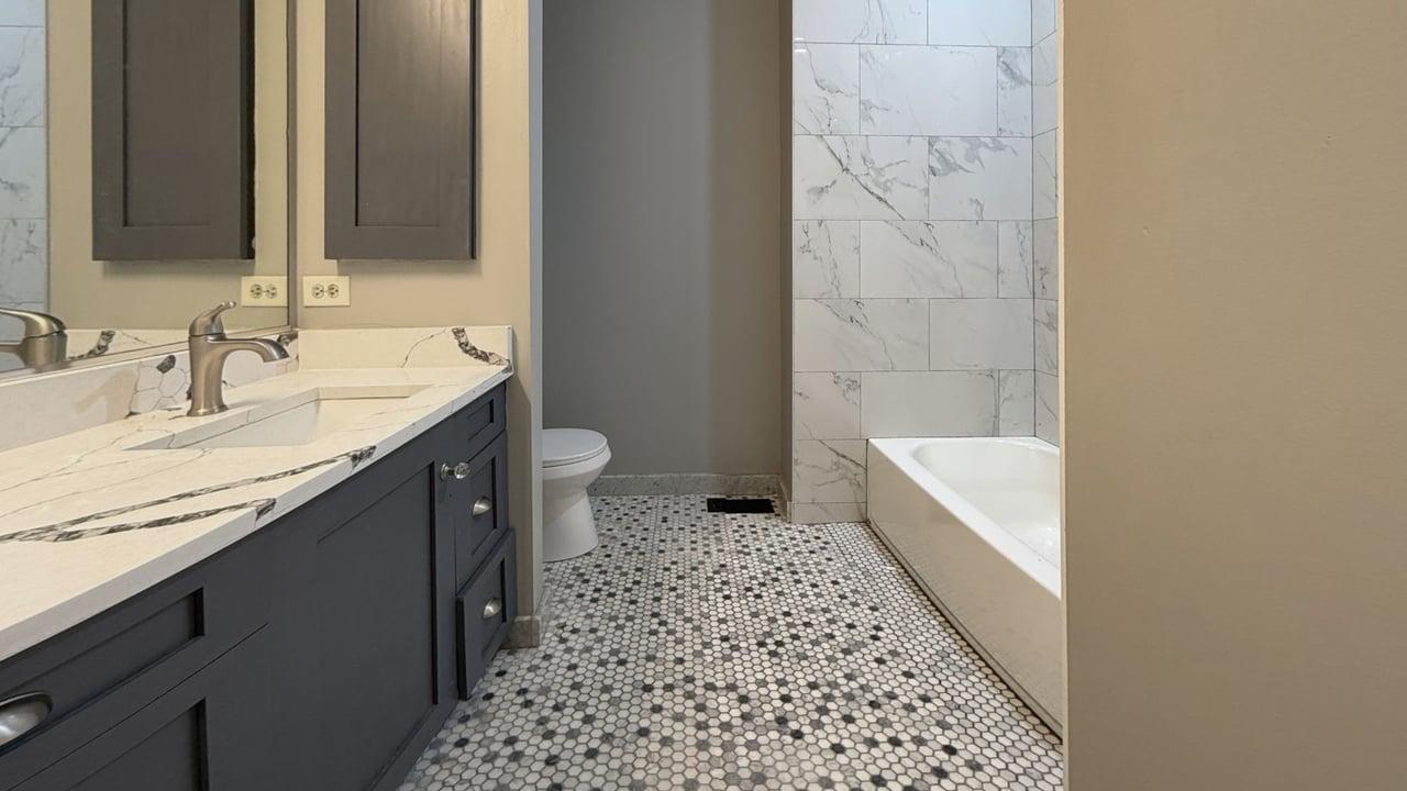 2350 West George Street, Unit 2350 Chicago, IL 60618 - Photo 12 of 21 a bathroom with a granite countertop sink a toilet a mirror a vanity and shower