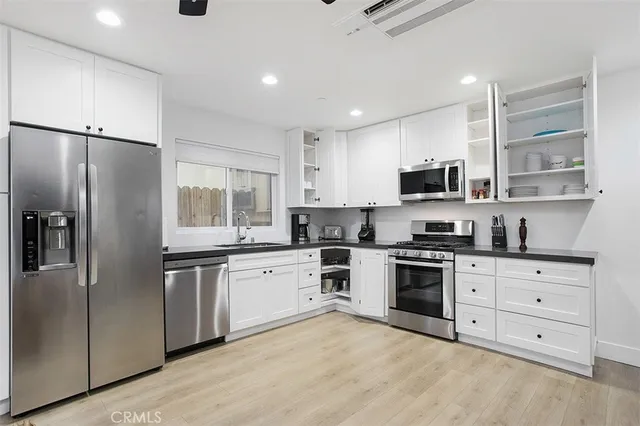 a kitchen with stainless steel appliances granite countertop a stove top oven a refrigerator and white cabinets