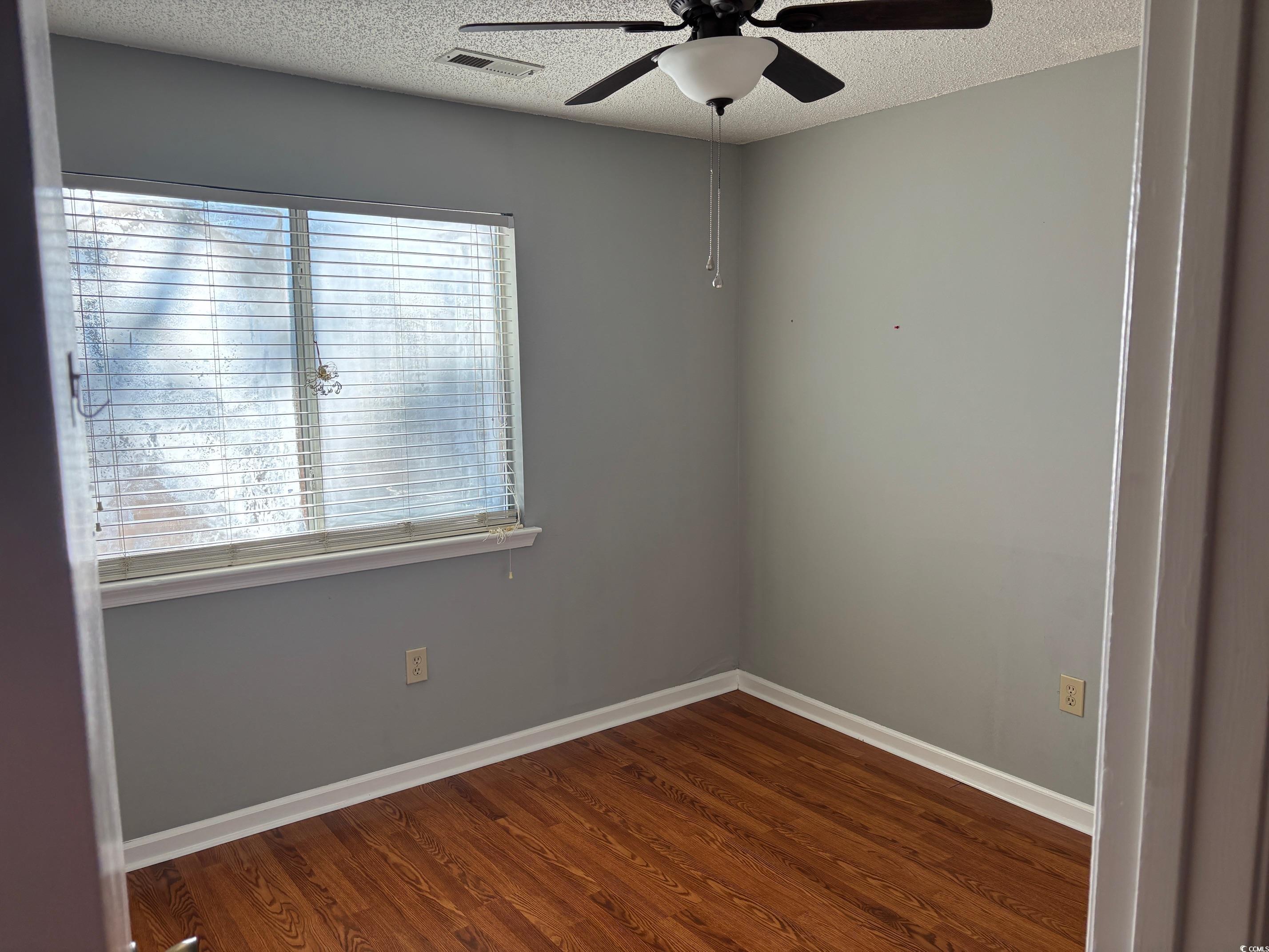 320 A Myrtle Greens Drive, Unit 320A Conway, SC 29526 - Photo 8 of 15 Unfurnished room with a ceiling fan, a textured ceiling, and dark wood-style flooring