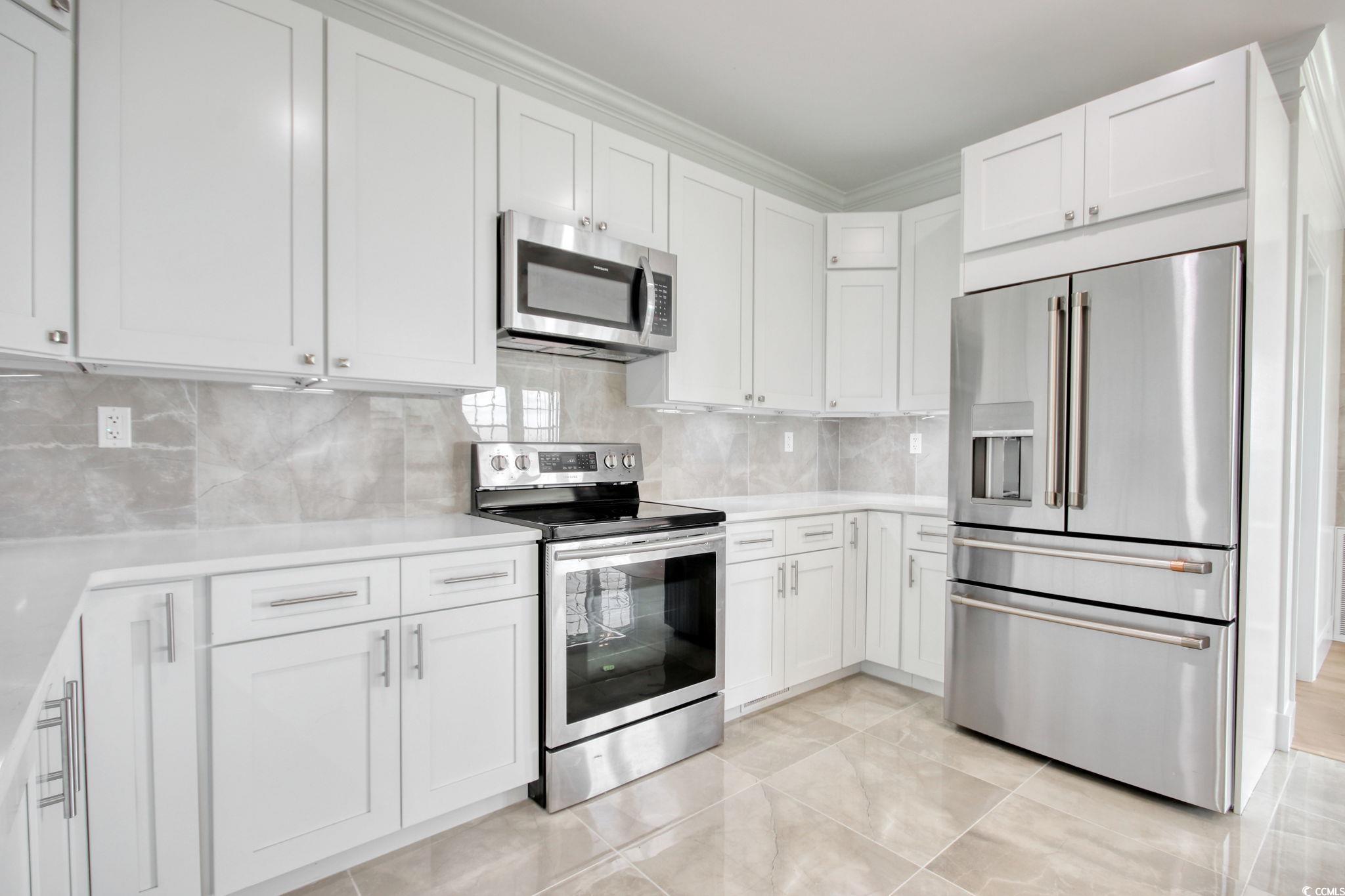 125 Oak Bay Drive Georgetown, SC 29440 - Photo 10 of 39 Kitchen with appliances with stainless steel finishes, light countertops, white cabinets, decorative backsplash, and crown molding