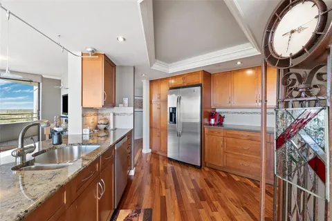 a kitchen with stainless steel appliances granite countertop a refrigerator a sink and wooden cabinets
