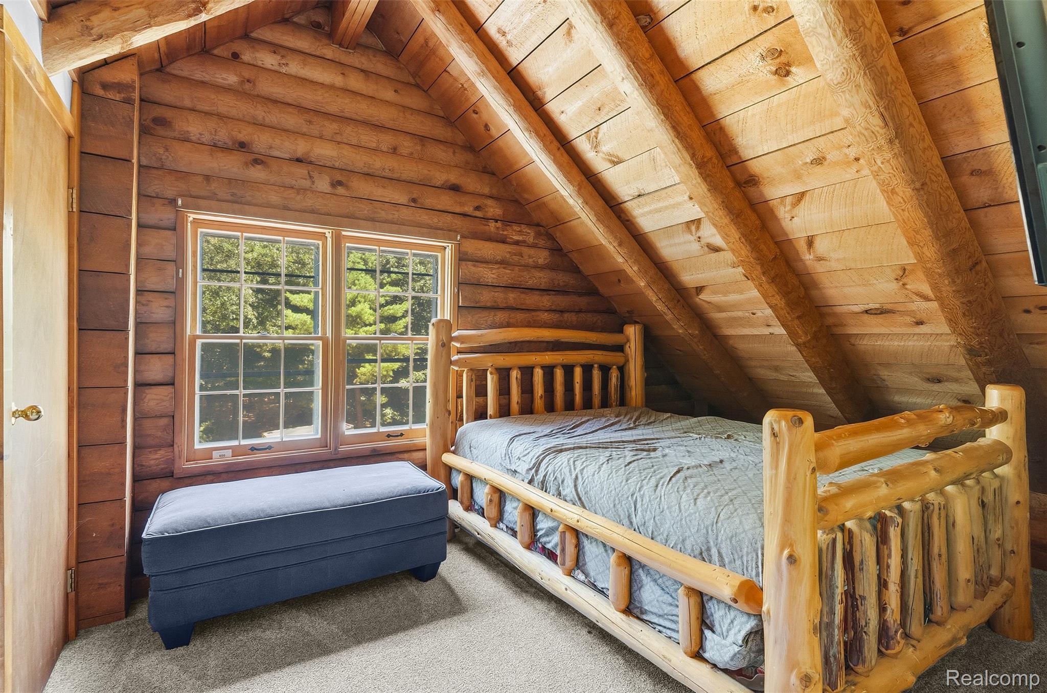 3656 Stanley Road Columbiaville, MI 48421 - Photo 28 of 65 Attic space featuring wood plank walls, exposed timber beams, a double-hung window with muntins, and light-colored carpeting