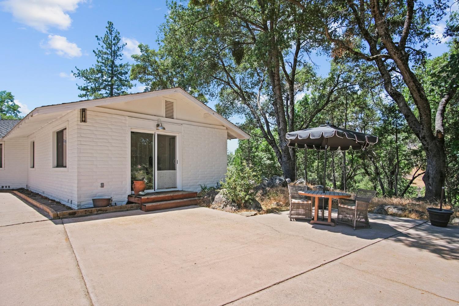 18950 Black Oak Road Sonora, CA 95370 - Photo 30 of 46 a backyard of a house with table and chairs under an umbrella