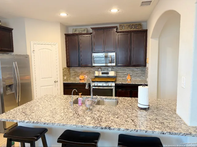 a kitchen with stainless steel appliances granite countertop a sink stove and refrigerator